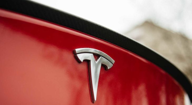 Tesla (TSLA) badge on back end of red Tesla car