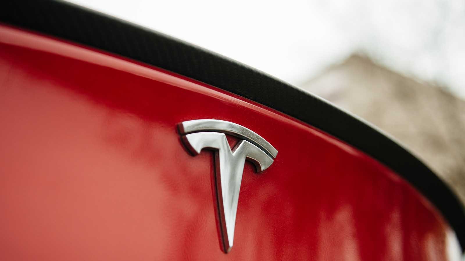 Tesla (TSLA) badge on back end of red Tesla car