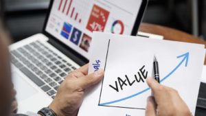 a person looks at an upward trending graph labeled "VALUE" to represent value stocks