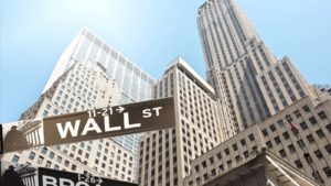 skyscraper buildings viewed from the ground with Wall Street street sign in the foreground