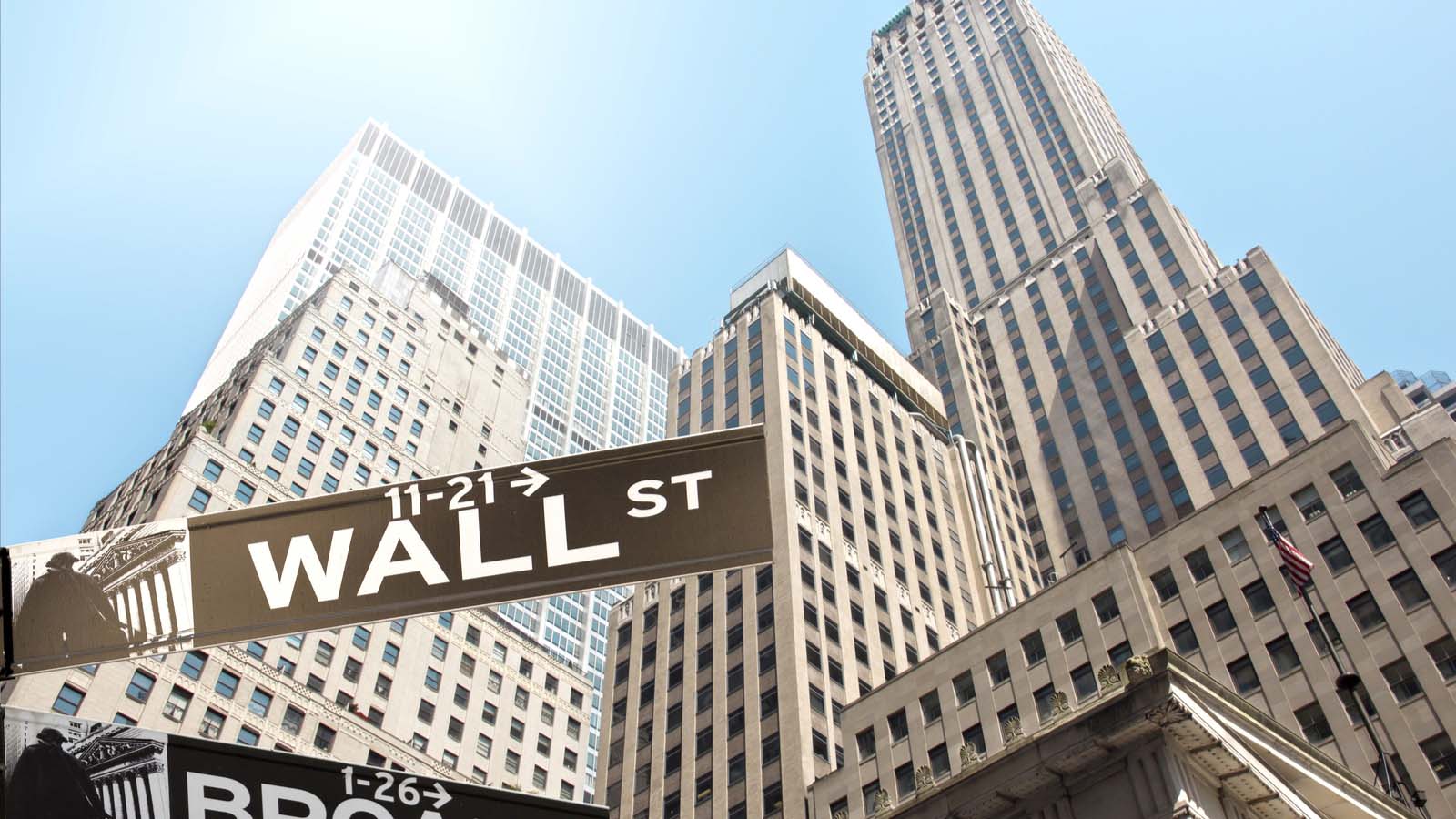 top stocks: skyscraper buildings viewed from the ground with Wall Street street sign in the foreground representing Pre-Market Stock Movers.