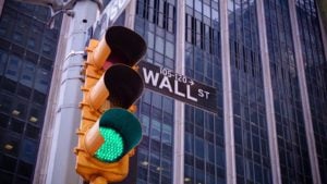 A traffic light flashes green in front of Wall Street.