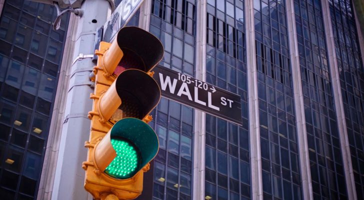 A traffic light flashes green in front of Wall Street.