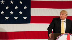 Photo of Donald Trump standing at a podium with the American flag in the background representing PHUN Stock.