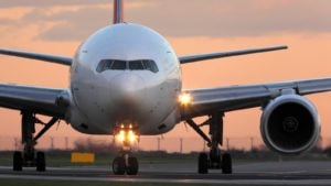 The front view of a passenger airplane with a sunset in the background.