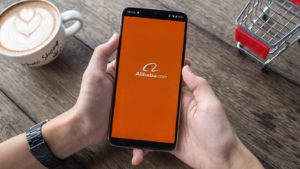 Alibaba (BABA) logo displayed on phone screen in person's hands