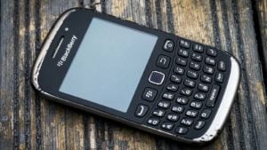 An image of a slightly damaged BlackBerry Curve on a wood surface.