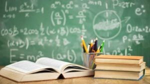 text books on a desk with a chalkboard in the background 