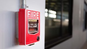 A photo of a red pull down fire alarm attached to the wall inside a building.