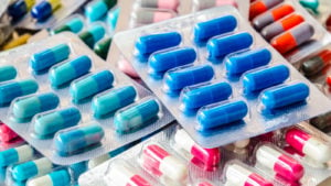 Packs of blue and pink pills are piled on top of each other.