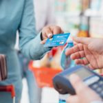 Woman at the supermarket checkout, she is paying using a credit card, shopping and retail concept. Best Retail Stocks to Buy