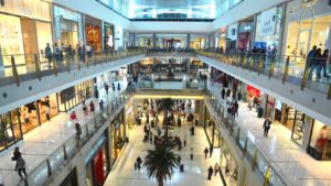 the interior of a crowded shopping mall representing Retail Stocks.