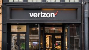 Verizon (VZ) logo above the entrance to a Verizon store.