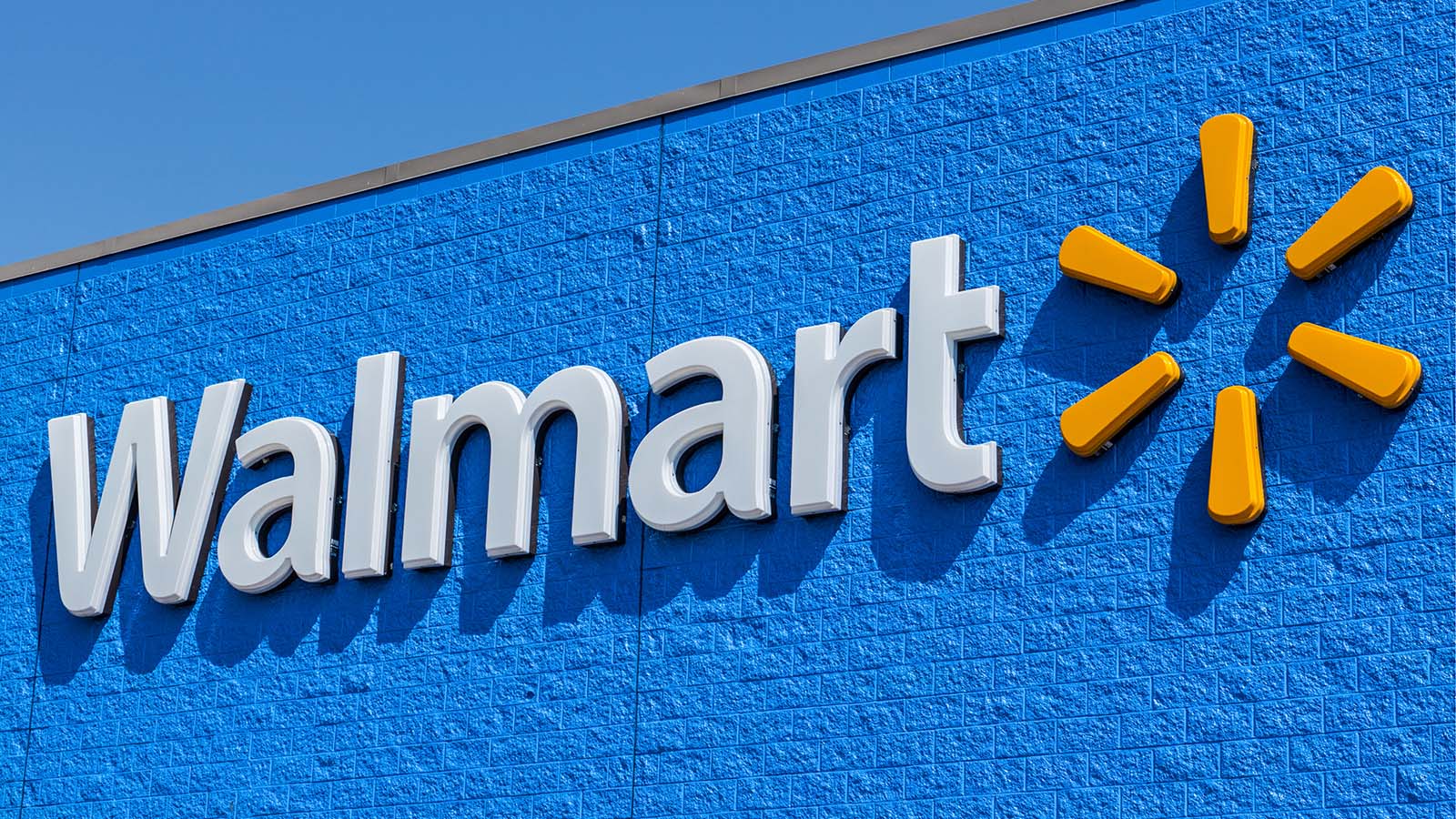 Image of Walmart (WMT stock) logo on Walmart store with clear blue sky in the background