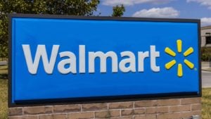 The blue, white, and yellow Walmart (WMT) logo is being displayed on a small rectangle sign in the grass.
