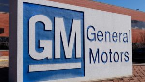 General Motors (GM) sign with blue and white logo and brick building in background