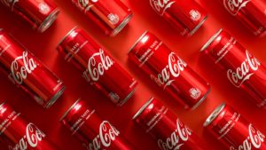 Close-up of Coca Cola drink cans lying on paper background. KO stock