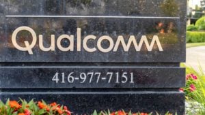 An image of a black marble sign surrounded by flowers and grass with the text "Qualcomm" and "416-977-7151" on it in a silver font.