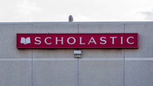 Image of a red Scholastic (SCHL) sign on the side of a building.