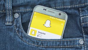 Snapchat (SNAP) logo on phone screen in jean pocket