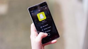 smart phone in hand with Snapchat (SNAP) logo on screen