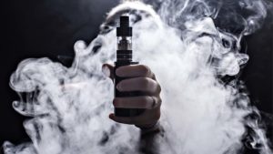 a vaping device held in a cloud of vapor