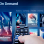 a hand pointing a remote control at a tv with a streaming service on the screen. DIS and ROKU are major streaming services