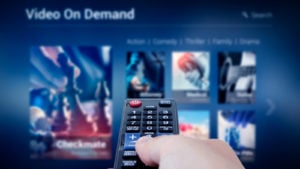 a hand pointing a remote control at a tv with a streaming service on the screen