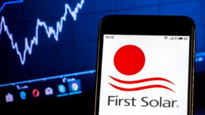 First Solar logo on smartphone in front of computer screen with graphs