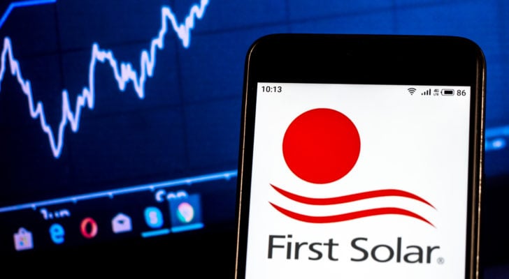 First Solar logo on smartphone in front of computer screen with graphs. FSLR stock