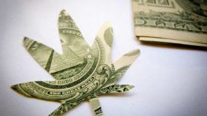 Dollar cut out in the shape of a marijuana leaf, used in HEXO stock article