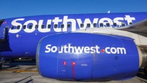 An image of the side of a blue Southwest plane with a blue sky in the background.