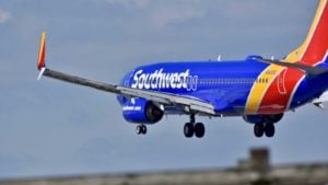 An image of a blue, yellow, and red Southwest plane taking off on a clear day.