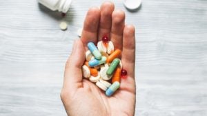 A close-up shot of a hand holding a variety of pills representing MEDS stock.