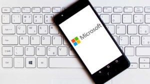 the Microsoft (<b><a href='/stocks/MSFT'>MSFT</a></b>) logo displayed on smartphone which is laying on top of a keyboard. symbolizes MSFT stock and blue-chip stocks