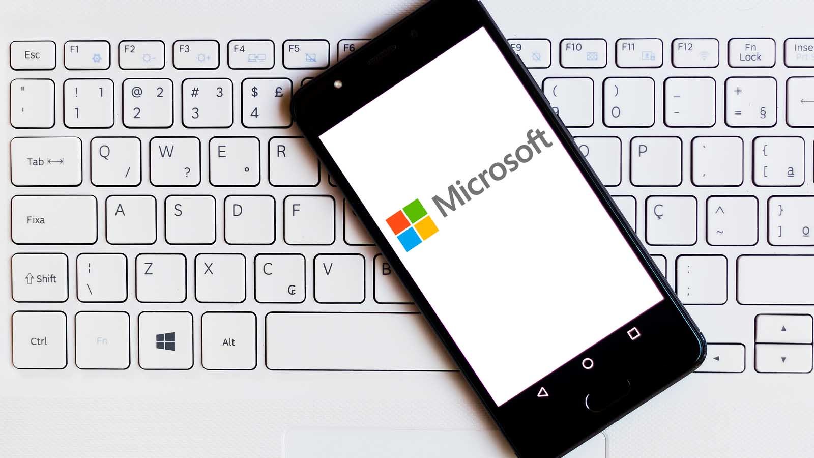the Microsoft (MSFT) logo displayed on smartphone which is laying on top of a keyboard. symbolizes MSFT stock and blue-chip stocks