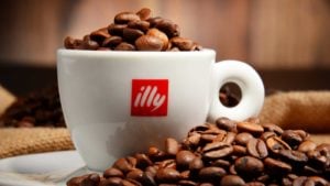 Image of a white illy branded coffee cup with light roast coffee beans inside of it and outside of