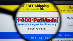 pets stock: petmeds express company logo on a screen, viewed through a magnifying glass