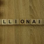 An image of letter blocks spelling out "Billionaire" on a wooden surface. Stocks to Buy Now