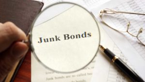 A magnifying glass zooms in on the word "Junk Bonds"