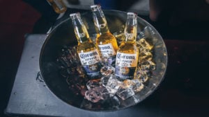 Three bottles of Corona beer are arranged in a bowl with ice.