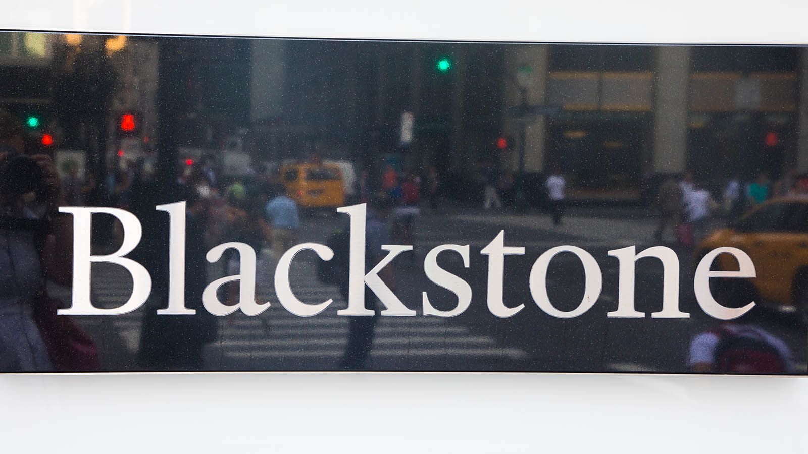 A sign for Blackstone (BX) hangs on a white wall.