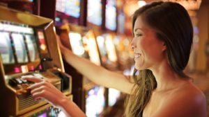 a woman smiling while using a slot machine in a casino. representing gambling stocks