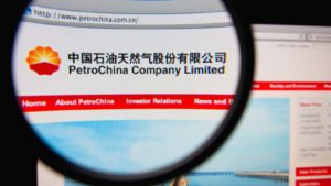 The logo for PetroChina (PTR) is displayed on the company's website viewed through a magnifying glass.