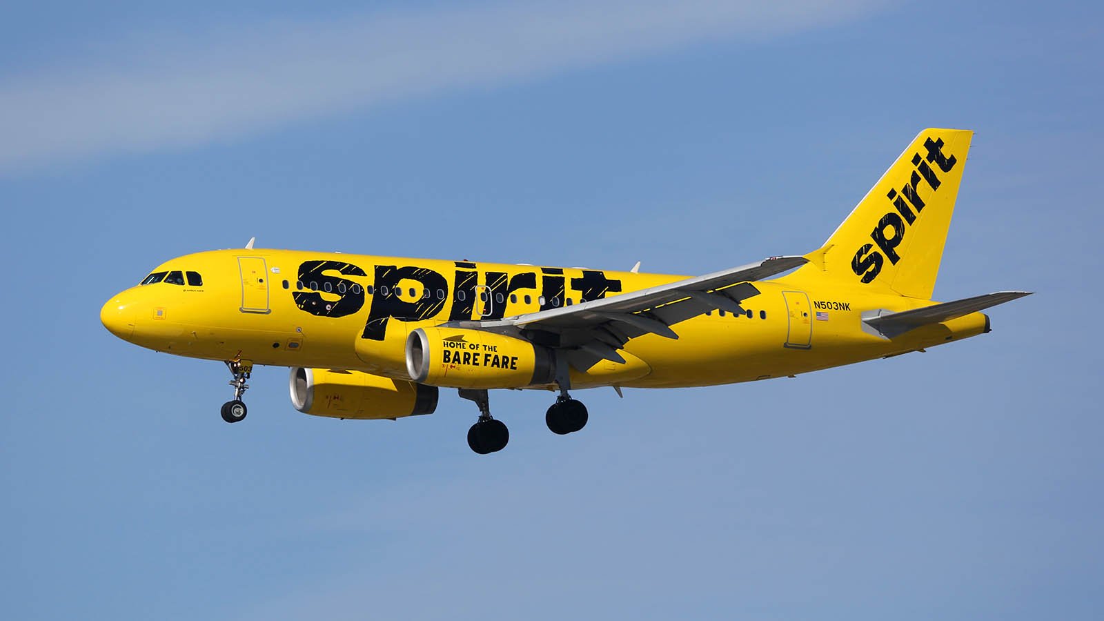 A yellow, Spirit Airlines (SAVE) branded airplane flying in the air