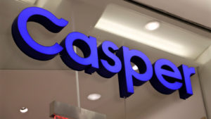 A bright purple sign for Casper Sleep (CSPR) hanging on a glass wall. 