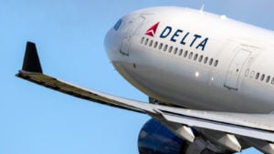 The Delta Air Lines (DAL) logo is seen on an airplane in flight representing Why Are Airline Stocks Down Today.