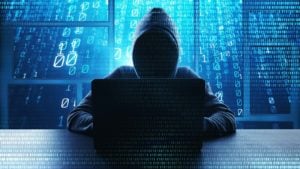 a faceless figure in a hoodie sitting in front of a laptop with lines of code in the background representing MNDT stock.