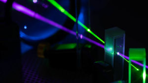 A photo of a purple and green laser going through an object