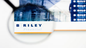 a magnifying glass enlarges the B. Riley (RILY) logo on a website